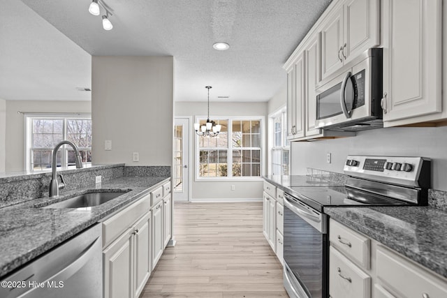 kitchen with stainless steel appliances, light wood-style floors, white cabinets, and a sink