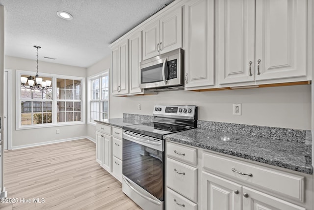 kitchen featuring appliances with stainless steel finishes, white cabinets, light wood-style flooring, and a textured ceiling