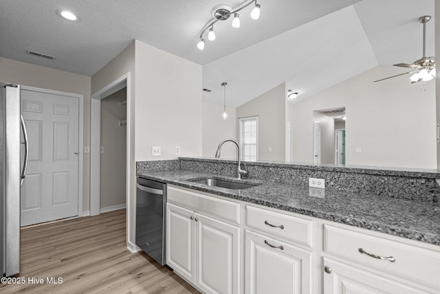 kitchen with a sink, visible vents, appliances with stainless steel finishes, light wood-type flooring, and dark stone counters