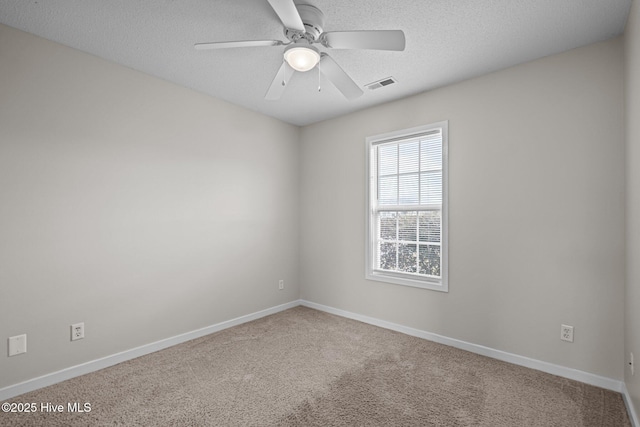 carpeted empty room with a textured ceiling, a ceiling fan, visible vents, and baseboards