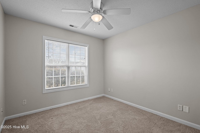 empty room featuring a textured ceiling, carpet flooring, visible vents, and baseboards