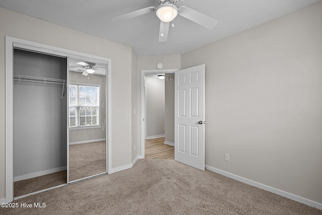 unfurnished bedroom featuring a closet, a ceiling fan, carpet flooring, a textured ceiling, and baseboards