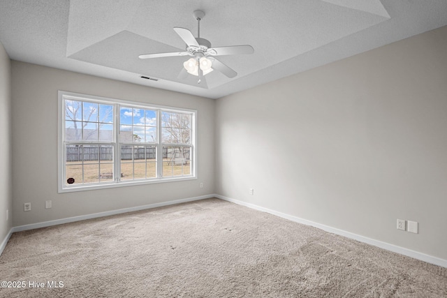 spare room with a textured ceiling, ceiling fan, visible vents, baseboards, and carpet