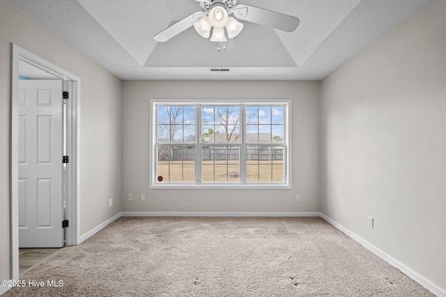 spare room featuring carpet floors, a raised ceiling, a textured ceiling, and baseboards