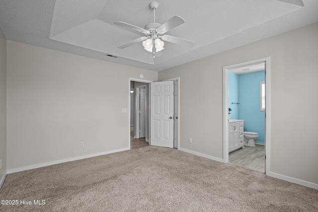 unfurnished bedroom featuring ensuite bathroom, carpet, visible vents, and baseboards