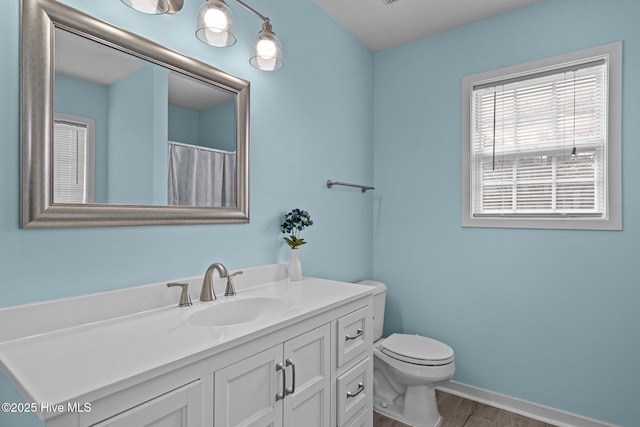 full bath featuring toilet, wood finished floors, vanity, and baseboards