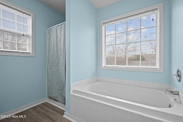 full bath with a shower with curtain, a garden tub, baseboards, and wood finished floors