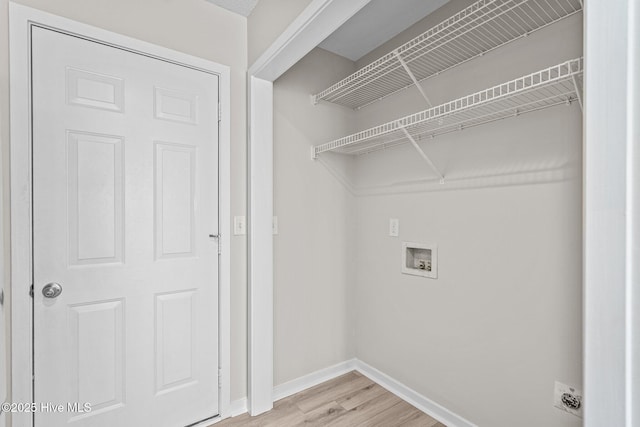 clothes washing area featuring laundry area, light wood finished floors, and baseboards