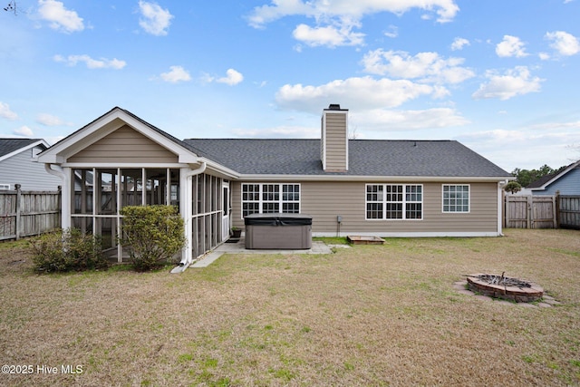 back of property featuring a yard, a chimney, a hot tub, a sunroom, and a fenced backyard