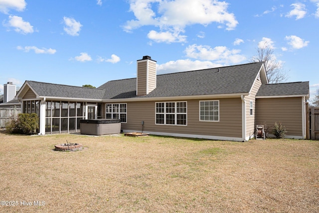 back of house with fence, a sunroom, a lawn, a chimney, and a hot tub