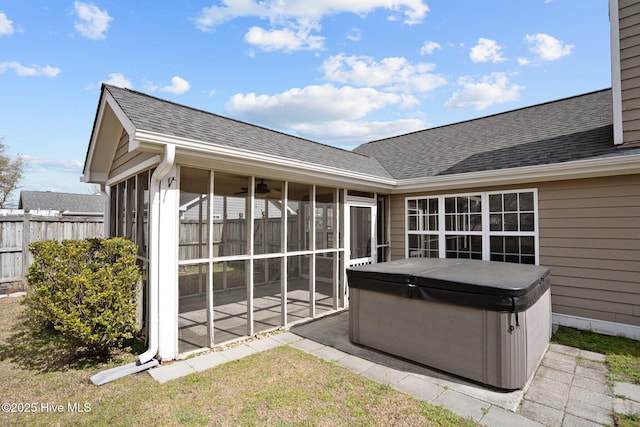 view of patio featuring a sunroom, fence, and a hot tub