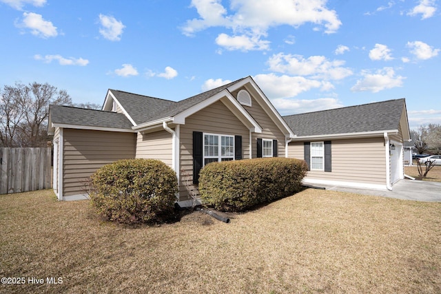 ranch-style house with a front lawn, roof with shingles, and fence