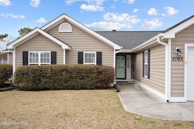 view of front of house featuring a shingled roof, a front yard, and an attached garage