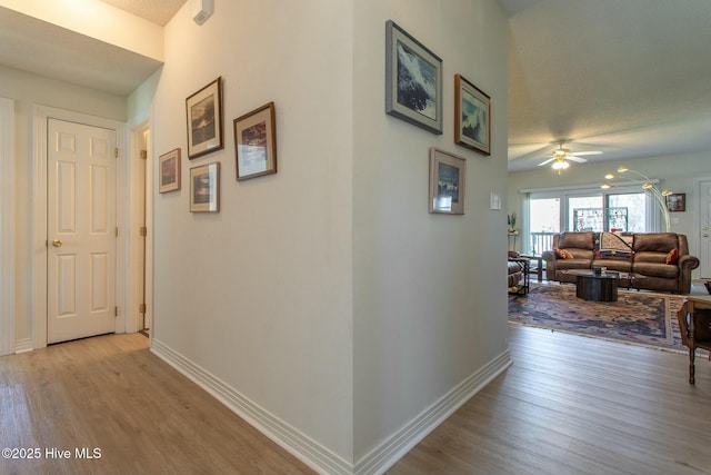 corridor featuring baseboards and wood finished floors