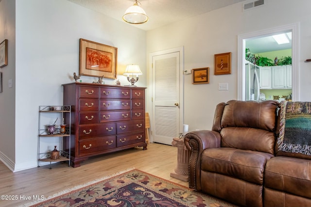 sitting room featuring light wood-type flooring, visible vents, and baseboards