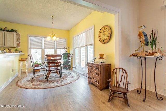 dining area featuring light wood-type flooring, an inviting chandelier, and baseboards