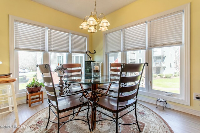 dining area with baseboards, a notable chandelier, and wood finished floors