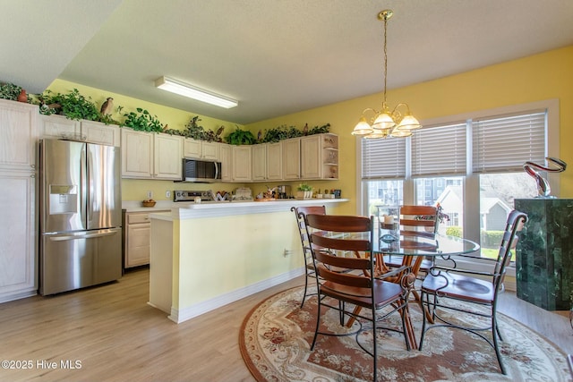 kitchen featuring a chandelier, light wood-style flooring, light countertops, appliances with stainless steel finishes, and pendant lighting