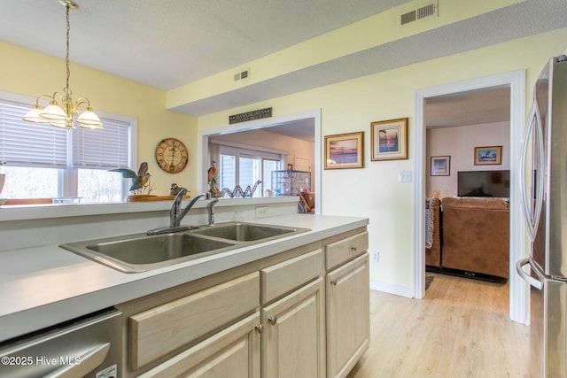 kitchen featuring light countertops, visible vents, freestanding refrigerator, a sink, and dishwasher