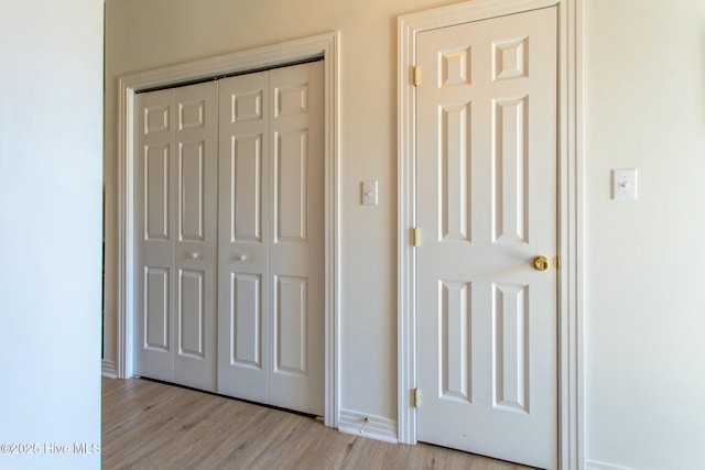 interior space with light wood finished floors, baseboards, and a closet