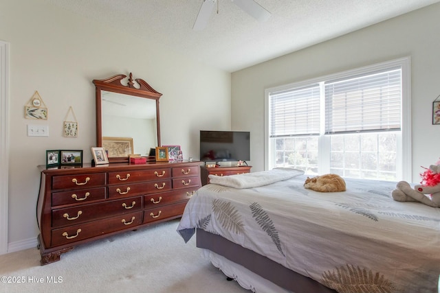 carpeted bedroom featuring ceiling fan and a textured ceiling