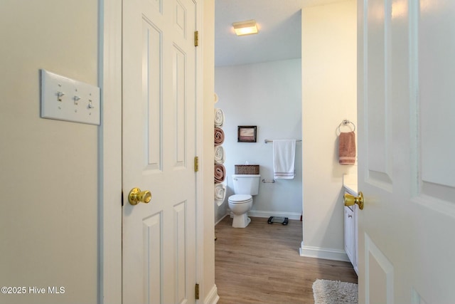 bathroom with wood finished floors, toilet, and baseboards