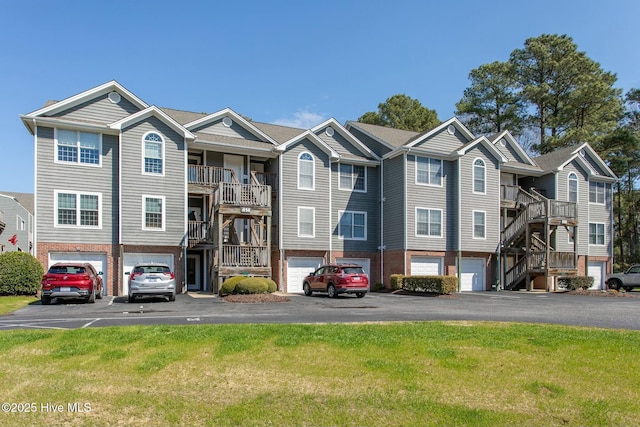 multi unit property with driveway, a residential view, an attached garage, a front lawn, and brick siding