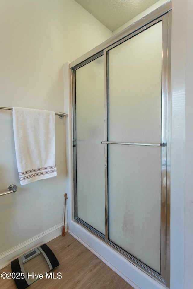 bathroom with visible vents, a shower with door, baseboards, and wood finished floors