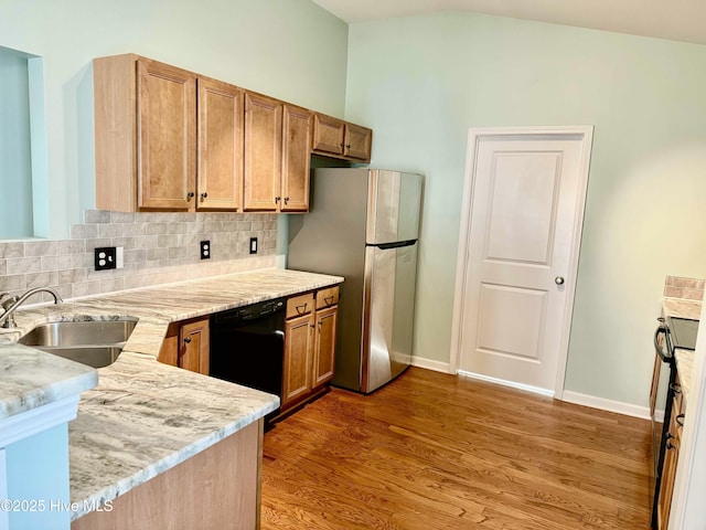 kitchen with dishwasher, decorative backsplash, freestanding refrigerator, wood finished floors, and a sink