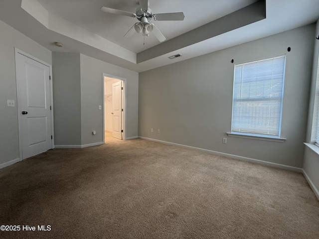 unfurnished bedroom with visible vents, a raised ceiling, a ceiling fan, carpet flooring, and baseboards