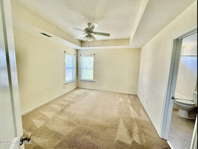 interior space featuring light colored carpet, baseboards, a raised ceiling, and ceiling fan