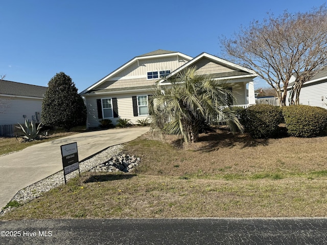 view of front facade with driveway, board and batten siding, and a front lawn