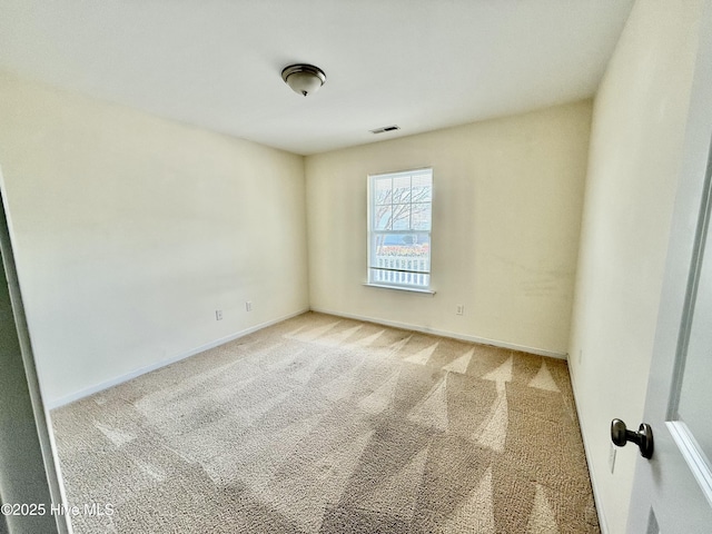 spare room featuring light colored carpet, visible vents, and baseboards