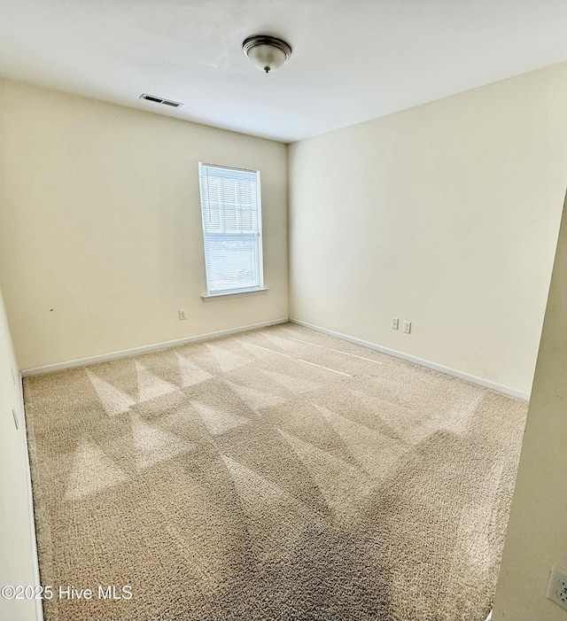 carpeted spare room featuring visible vents and baseboards