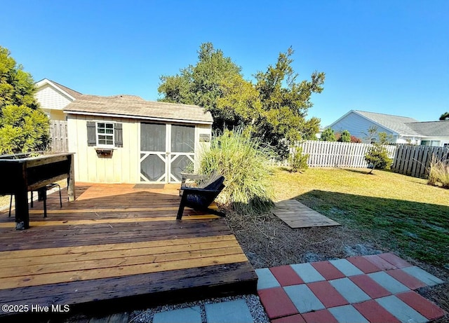 view of yard with an outbuilding, a shed, a fenced backyard, and a deck