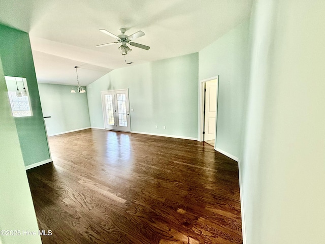 unfurnished room featuring baseboards, lofted ceiling, dark wood-type flooring, and ceiling fan with notable chandelier