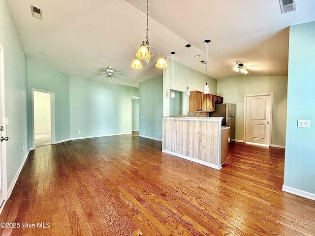 kitchen featuring visible vents, ceiling fan with notable chandelier, freestanding refrigerator, and vaulted ceiling