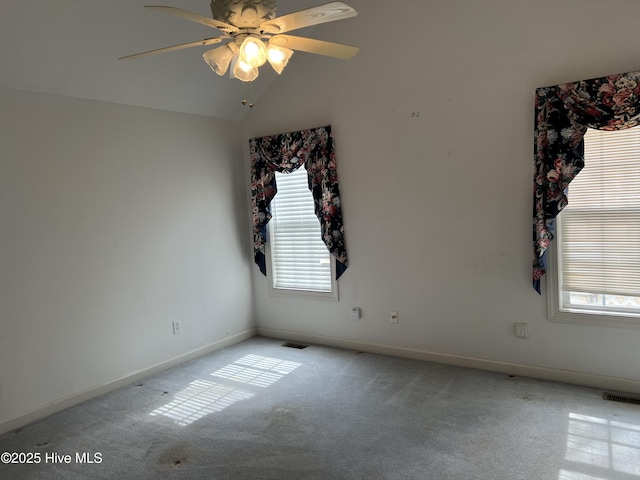 carpeted empty room featuring lofted ceiling, visible vents, ceiling fan, and baseboards