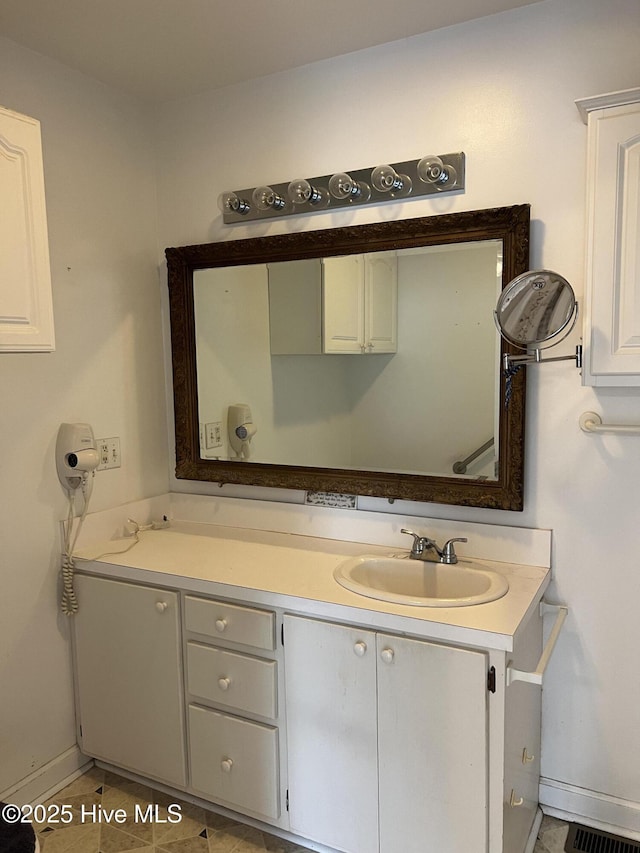 bathroom featuring visible vents, baseboards, and vanity