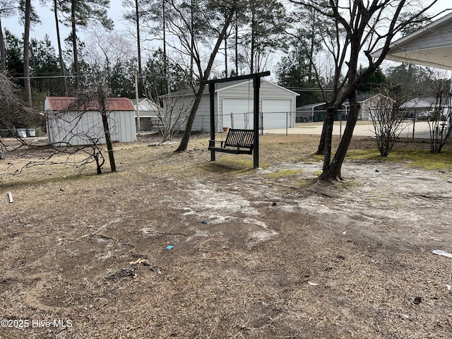 view of yard featuring a detached garage, fence, and an outdoor structure