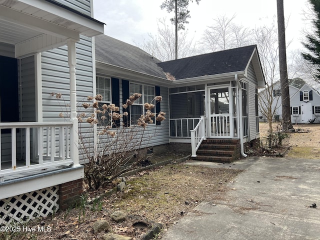 exterior space with a sunroom, a porch, and roof with shingles