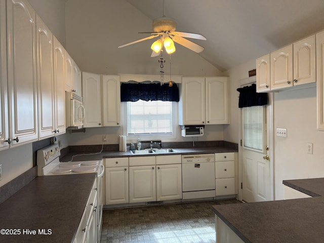 kitchen featuring white appliances, dark countertops, lofted ceiling, white cabinetry, and a sink