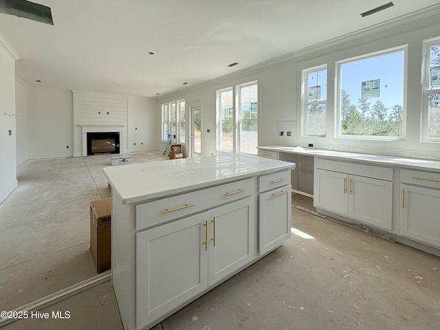 kitchen featuring plenty of natural light, a center island, a large fireplace, and ornamental molding