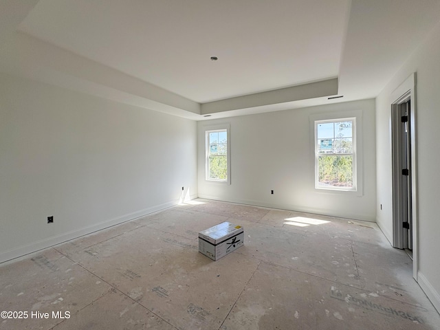 spare room with baseboards and a raised ceiling