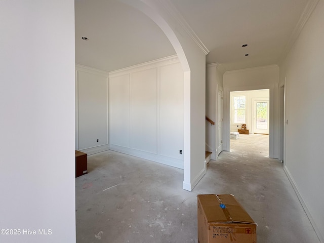 corridor featuring unfinished concrete flooring, arched walkways, ornamental molding, and a decorative wall