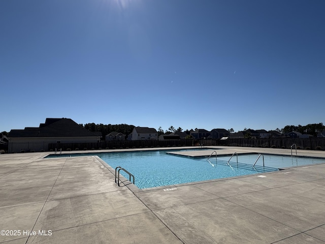 pool with a patio area and fence