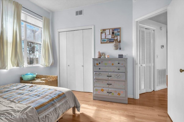 bedroom featuring light wood-type flooring, visible vents, and a textured ceiling