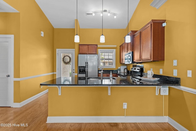 1036 Tideline Dr, Leland, NC 28451 - kitchen with appliances with stainless steel finishes, a peninsula, brown cabinets, light wood-style flooring, and vaulted ceiling