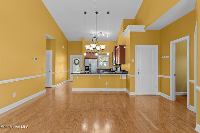 1036 Tideline Dr, Leland, NC 28451 - kitchen with stainless steel fridge with ice dispenser, high vaulted ceiling, a chandelier, light wood-style flooring, and a peninsula