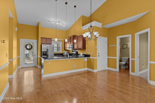 1036 Tideline Dr, Leland, NC 28451 - kitchen with stainless steel fridge with ice dispenser, a towering ceiling, a peninsula, light wood-type flooring, and dark countertops